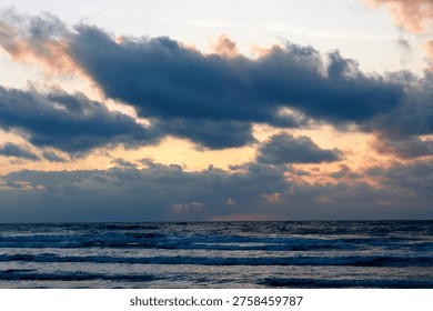 Dramatic sunset over stormy ocean waves with crepuscular rays and flying birds