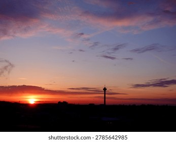Dramatic sunset over Tampere, Finland, with Näsinneula silhouetted against a colorful sky. Serene Nordic cityscape with warm evening light.