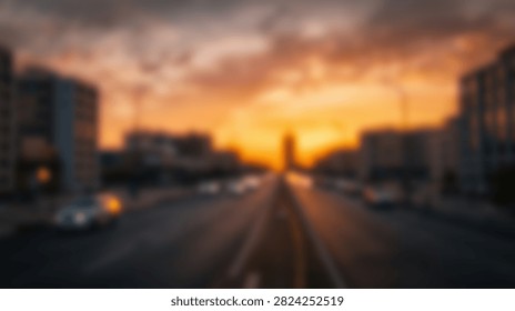 A dramatic sunset paints the sky with vibrant orange hues over a blurred cityscape, with buildings and streetlights visible.