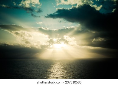 Dramatic Sunset Rays Through A Cloudy Dark Sky Over The Ocean