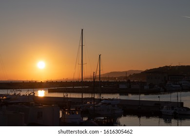 Dramatic Sunset Seen From A Harbor With Multiple Sailboats And Ships