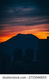 Dramatic sunset sky behind mountain silhouette and urban skyline