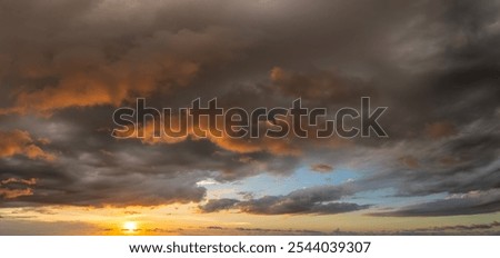 Dramatic sunset sky covered with colorful yellow clouds. Panoramic skyscape