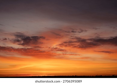 Dramatic sunset sky creating a vibrant natural background with warm orange, red, and yellow colors above a dark silhouette horizon, presenting a peaceful and atmospheric scene