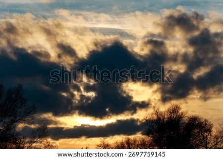 Dramatic sunset sky with a dark cloud resembling a monstrous face. Eerie natural pareidolia amidst golden and dusky hues, sparking imagination