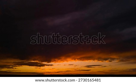 Dramatic sunset sky with dark clouds and glowing horizon. Dark moody sunset sky without land, cinematic natural background with copy space for design.