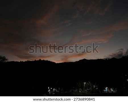 Dramatic sunset sky with dark clouds over hill silhouettes, creating emotional and peaceful evening atmosphere in nature.