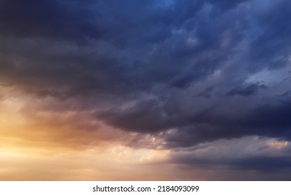 Dramatic sunset sky with dark rainy clouds and bright sunshine.
