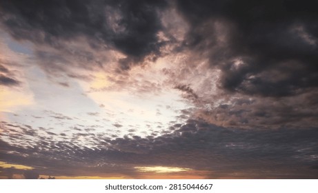 A dramatic sunset sky filled with textured clouds and soft golden light breaking through the dark atmosphere.