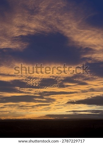 A dramatic sunset sky with golden and deep purple clouds. A wide-angle landscape that captures the majesty of atmospheric phenomena.