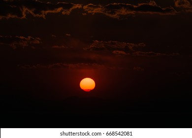 Dramatic sunset sky with orange colored clouds and sun.