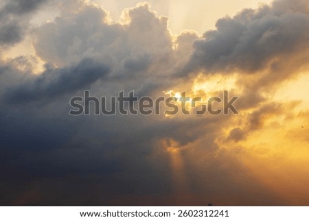 Dramatic sunset sky over Caribbean Sea with dark storm clouds and golden sun rays breaking through. Mexico.