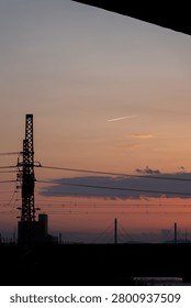 Dramatic sunset sky over distant mountains and city silhouette layered with electrical power lines and overhead wires, Japan.