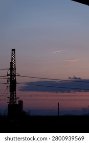 Dramatic sunset sky over distant mountains and city silhouette layered with electrical power lines and overhead wires, Japan.