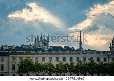 Dramatic sunset sky over a historic city building with sun rays breaking through the clouds. Urban landscape mixing heritage architecture and natural beauty.