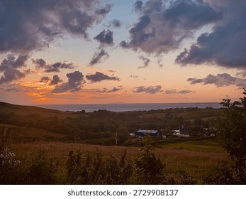 Dramatic sunset sky over rolling countryside hills and rural landscape farmland.