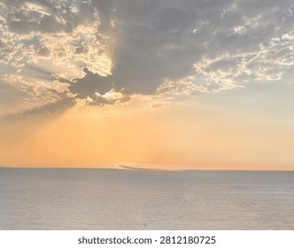 Dramatic sunset sky with powerful sun rays peeking through clouds over the sea in Dubai, UAE.