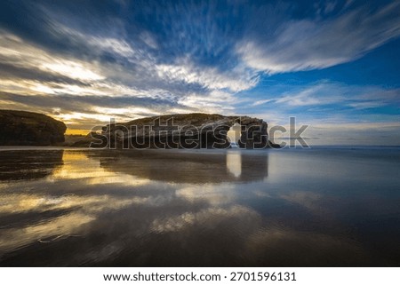 Dramatic sunset sky reflection at Playa de las Catedrales beach, in Lugo, Galicia, Spain