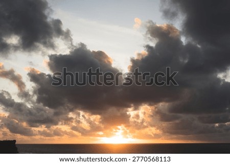 Dramatic sunset with sun breaking through dark storm clouds, Bali