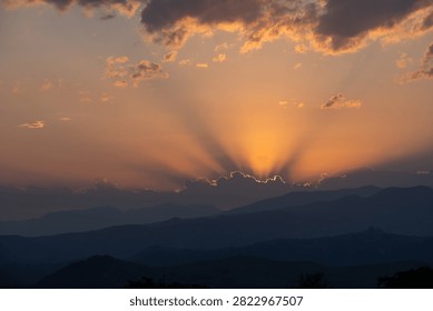 Dramatic Sunset Sun Rays Over Mountain Range and Clouds.