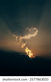 Dramatic sunset with sun rays piercing through clouds in a vibrant sky.