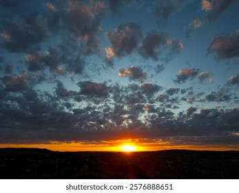 A dramatic sunset with vibrant clouds over a silhouetted landscape
