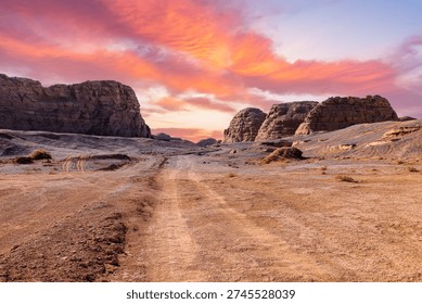 Dramatic sunset view over a desert road and rock formations in the arid landscape of Xinjiang, China.