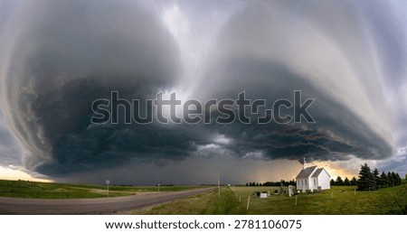A dramatic supercell storm cloud formation approaches a rural landscape with a small church and graveyard, creating an ominous atmosphere