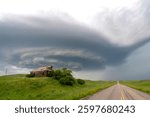Dramatic supercell thunderstorm cloud forming over an abandoned farmhouse and a country road in the prairies