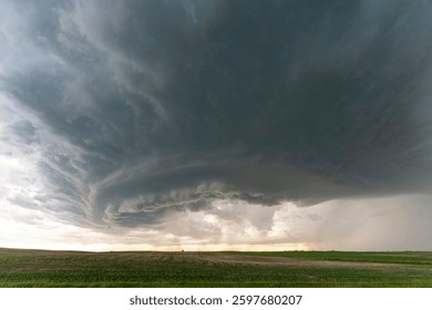 Dramatic supercell thunderstorm forming over a green field