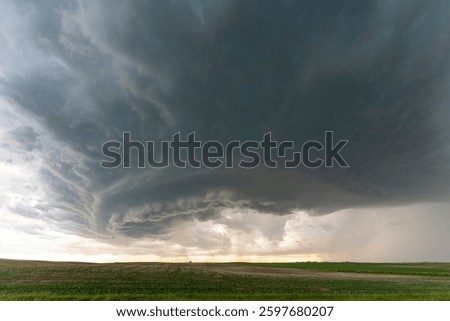 Dramatic supercell thunderstorm forming over a green field