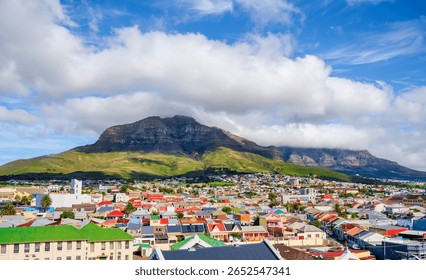 A dramatic tablecloth of clouds covers Table Mountain and Devil's Peak, creating a stunning backdrop for the colorful houses of the Woodstock suburb, Cape Town, South Africa