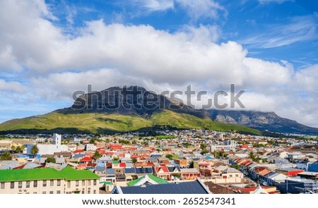 A dramatic tablecloth of clouds covers Table Mountain and Devil's Peak, creating a stunning backdrop for the colorful houses of the Woodstock suburb, Cape Town, South Africa