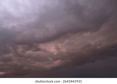 Dramatic thunderstorm with dark clouds in the evening. Dramatic sky of clouds reflecting strong hues of orange, pink, blue and yellow lighting up