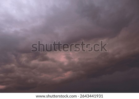 Dramatic thunderstorm with dark clouds in the evening. Dramatic sky of clouds reflecting strong hues of orange, pink, blue and yellow lighting up