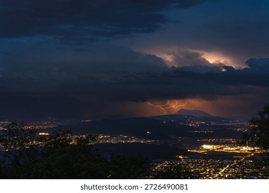 A dramatic thunderstorm electrifies the night sky over the Seetal valley, with a brilliant bolt of lightning illuminating the iconic Rigi mountain range in Switzerland.