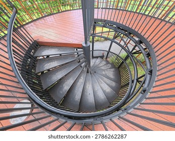 a dramatic top down view of a modern spiral staircase with sleek black metal railing and geometric symmetry