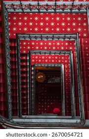 Dramatic top-down shot of a red staircase, highlighting bold color, geometric shapes, and architectural design. Ideal for abstract photography, architecture, and modern design enthusiasts.