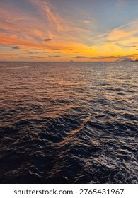 Dramatic twilight sky over deep blue sea water with golden horizon.