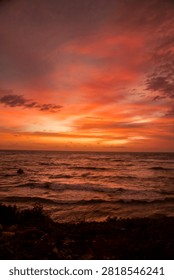 Dramatic twilight sky over the ocean horizon during sunset at a rocky beach coast in Bali.
Stunning dramatic red and orange sunset sky over the ocean horizon in Bali, Indonesia.
Beautiful tropical golden hour sunset view from a coastal cliff overlooking the sea waves.