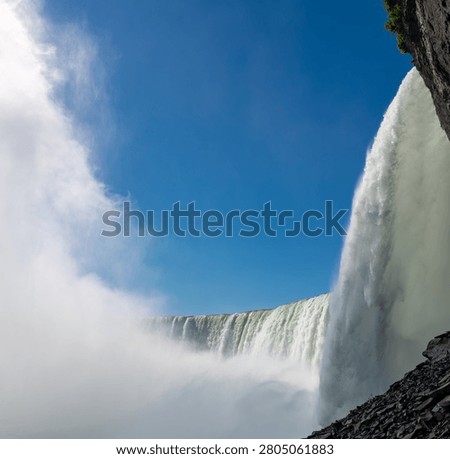 Dramatic Upward View From Behind Niagara Horseshoe Falls With Mist and Blue Sky
