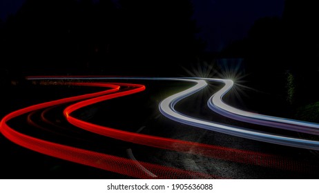 Dramatic vehicle light trails through a village road.