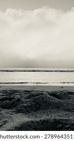 A dramatic, vertical black and white perspective of a dense fog bank rolling into the coast in Carlsbad, California
