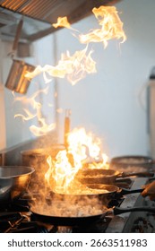 Dramatic vertical flame with chef cooking intensely in commercial kitchen.