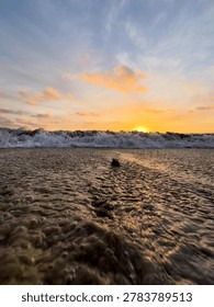 A dramatic, vertical portrait of a dusky sunset low over the water at the beach in Carlsbad, California.