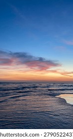 Dramatic Vertical Sunset Over the Ocean with Pink Clouds and Blue Sky Gradient.