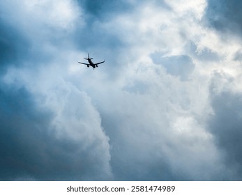 Dramatic view of an airplane flying through a moody,storm-like clouds.The aircraft is silhouetted against the bright yet turbulent atmosphere,creating a sense of adventure,travel, and mystery.