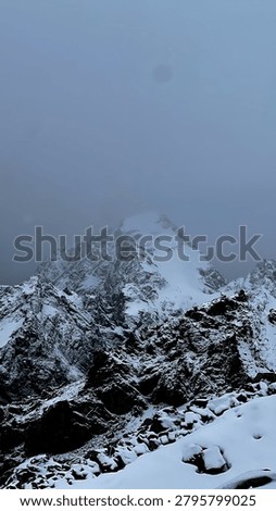 Dramatic view of Aoraki Mount Cook, the highest Mountain in New Zealand, partially covered by mist and fresh snow. Ruged alpine  peaks and rocky foreground create a moody winter landscape in Aoraki Mount Cook National Park, South island, New Zealand