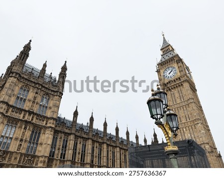 Dramatic view of Big Ben and the Gothic Houses of Parliament with an ornate street lamp in London, UK.
