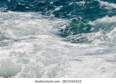 Dramatic view of churning ocean waves with white sea foam and deep blue water in rough sea